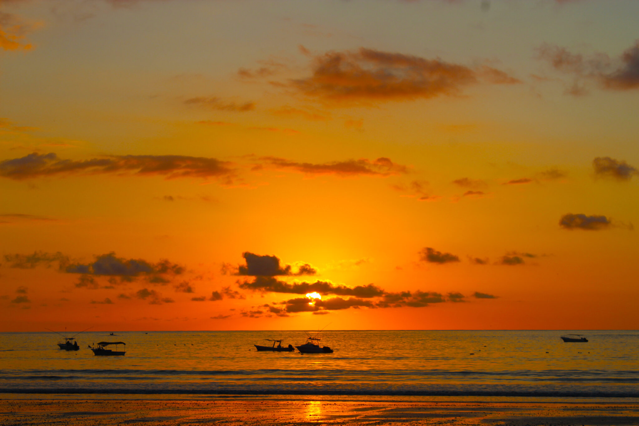 Golden sunset with boats floating on the ocean in Playa Sámara, Costa Rica