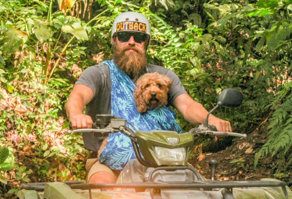 man riding atv with dog in carrier on jungle trail in la fortuna costa rica