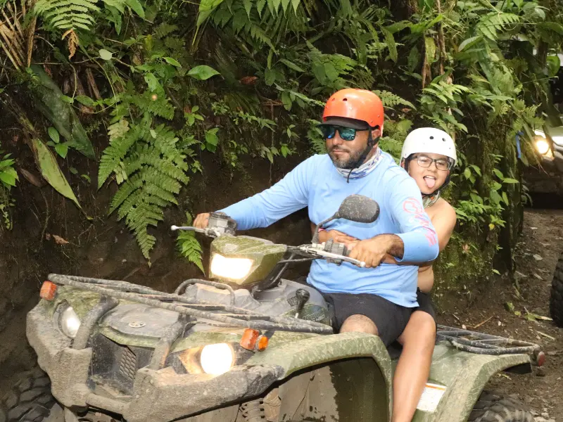 Father and daughter riding an ATV through jungle trails in La Fortuna, Costa Rica