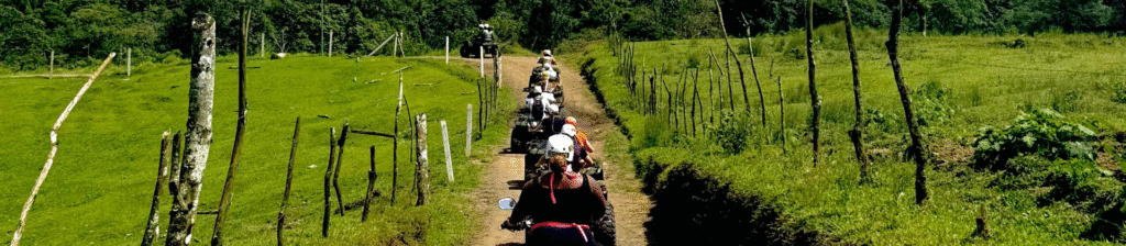 Group of travelers riding ATVs through rural trails near Arenal Volcano during an Outback Quads tour in La Fortuna Costa Rica.