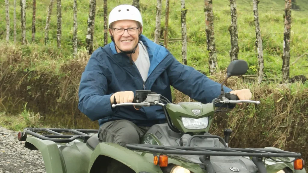Senior traveler smiling while riding an ATV on a scenic trail in La Fortuna, Costa Rica.