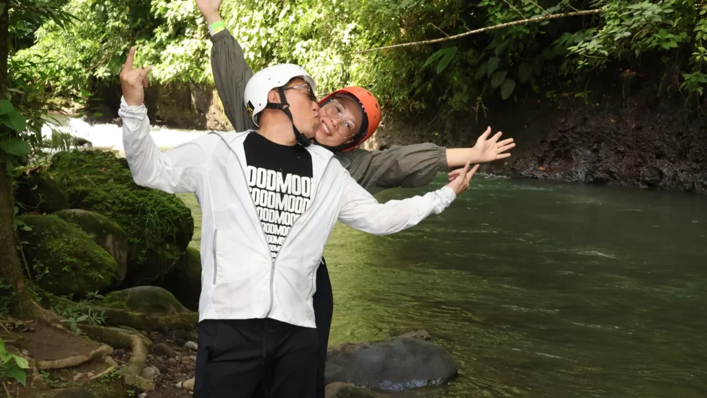 Couple wearing helmets enjoying a river stop during a guided ATV tour near La Fortuna, Costa Rica.