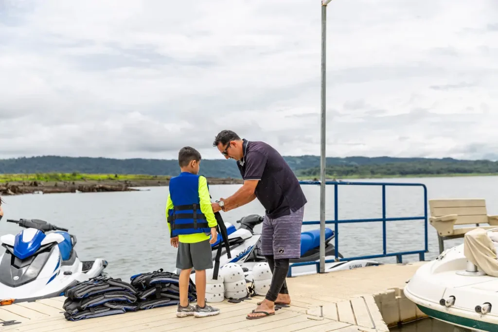 Guide assisting a child with safety gear before a jet ski tour in La Fortuna, Costa Rica.
