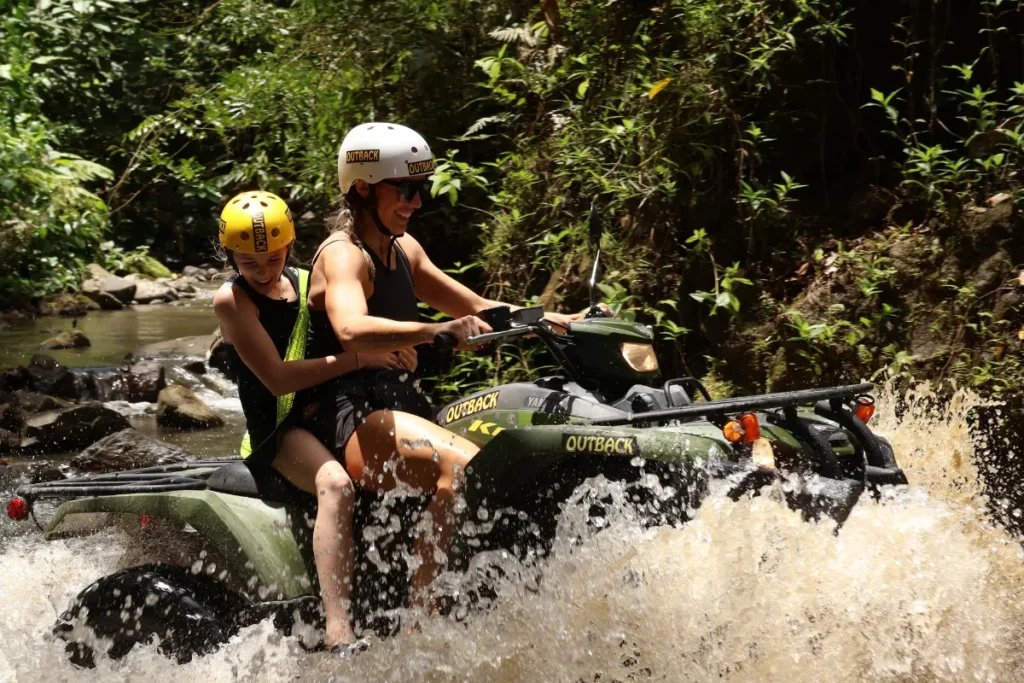 Couple crossing a river during an ATV tour in La Fortuna, Costa Rica.