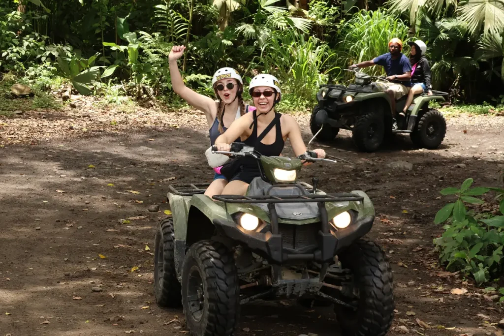 Friends smiling while riding an ATV on a rainforest trail in La Fortuna Costa Rica.