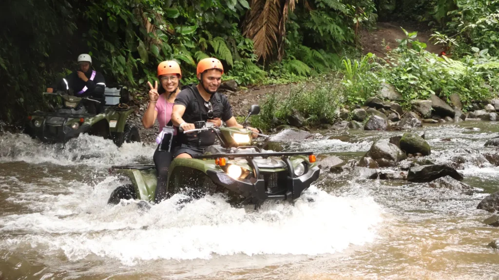 Family crossing a rocky river on an ATV tour in La Fortuna, Costa Rica